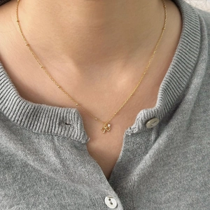 Close-up of a gold bow pendant necklace with zircon stone on a beaded chain for women