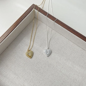 Detailed view of silver and gold heart pendants with starburst texture and small zircon