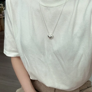 Gros plan d'un collier avec pendentif cœur en argent sur chaîne à boules en argent massif 925