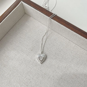 Detailed macro view of an S925 silver heart necklace with a sparkling starburst zircon inlay