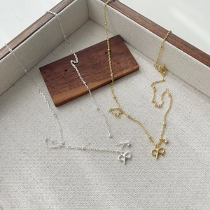 Macro detail of S925 silver and gold bow necklaces with crystals in a wooden tray