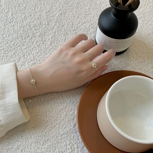 Close-up of S925 sterling silver daisy ring and bracelet on a hand in an elegant setting