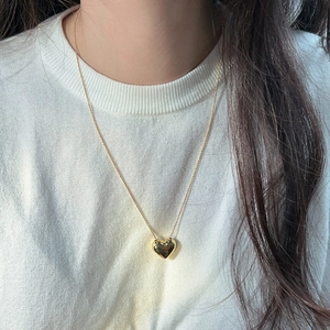 Vue macro détaillée d'un pendentif cœur doré 3D poli sur une fine chaîne à billes