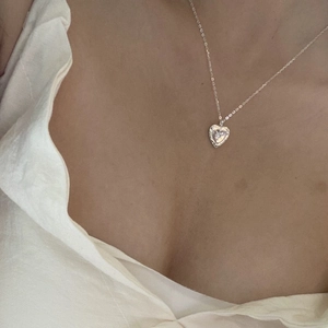 Close-up of minimalist silver heart pendant necklace with star motif on a female neck