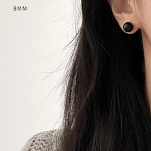 Detail view of an 8mm black onyx stud earring on ear with high gloss finish