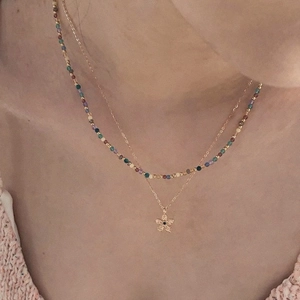 Détail d'un collier floral à deux rangs avec pierre noire et perles colorées sur un mannequin