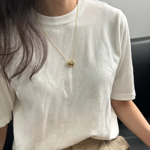 Gros plan d'un collier pendentif coeur en finition dorée sur fond blanc