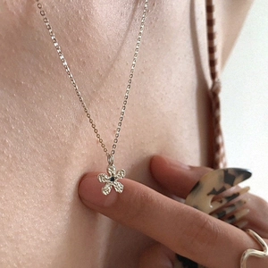 Gros plan d'un pendentif fleur argenté avec pétales texturés et diamant noir serti
