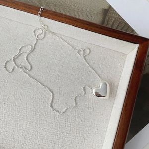 Détail du pendentif cœur en argent et chaîne à billes sur plateau d'exposition