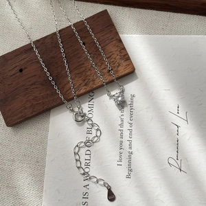 Detailaufnahme der S925 Silberhalskette mit CZ-Anhänger auf dunklem Holz und Dekopapier