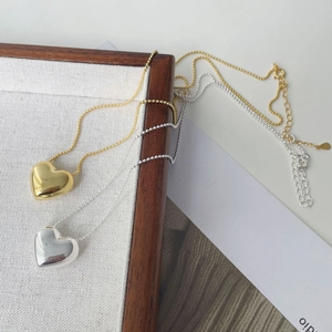 Détail de pendentifs cœur en argent et or sur chaînes à billes sur un plateau