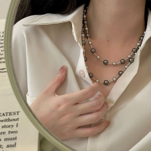 Close-up of double-layered necklace featuring dark grey pearls and silver metallic beads