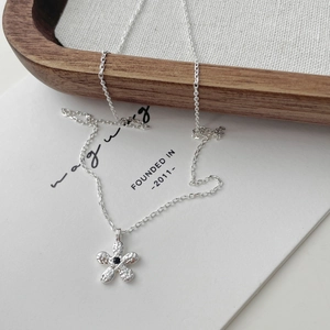 Détail du pendentif fleur à texture martelée et gemme noire sur chaîne argentée