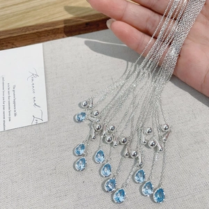 Detail of S925 silver necklace featuring a blue water drop pendant and layered chains