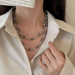 Close-up of double-layered gradient grey and silver pearl necklace worn by a model