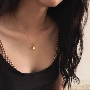 Gros plan d'un collier fleur doré avec pierre noire sertie porté par un mannequin