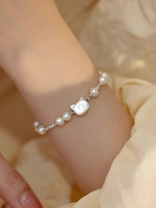 Detail showing freshwater pearls and cat shell charm on a silver beaded bracelet