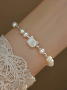 Detail of S925 silver bracelet with cat-shaped natural pearl on a wrist with lace