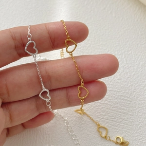 Detailed close-up of 925 silver heart bracelet showing golden and silver metal textures