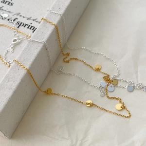 Detailed close-up of gold and silver minimalist circle necklaces on a textured fabric