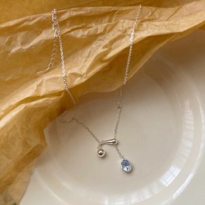 Detail of S925 silver necklace with blue water drop zircon on a natural paper background