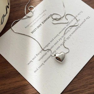 Close-up of polished S925 silver 3D heart pendant with elegant box chain on a card