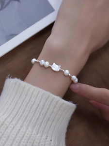 Detail view of S925 silver bracelet featuring natural shell cat charm and freshwater pearls