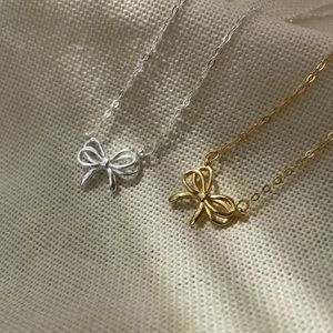 Macro shot of 925 sterling silver bow pendants in gold and silver finish on textured fabric