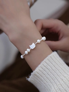 Detail of freshwater pearl bracelet with a cute shell cat charm on a model wrist