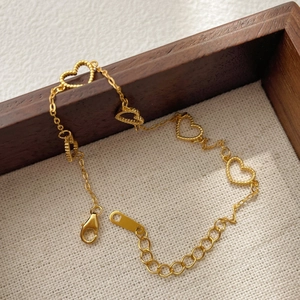 Detail of a 925 silver gold heart bracelet with five textured charms and lobster clasp