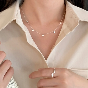 Close-up of minimalist silver necklace with mini round disc pendants on model neck