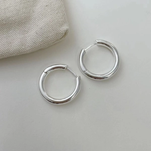 Gros plan de boucles d'oreilles créoles polies en argent avec pochette en toile