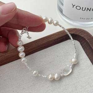 Detail shot of a pearl bracelet with silver beads and a cat-shaped shell charm