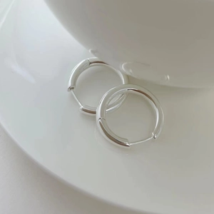 Gros plan de créoles minimalistes en argent sterling S925 avec une finition polie