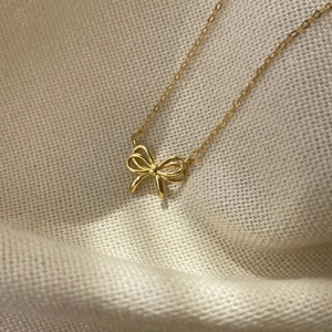 Macro shot of gold 925 sterling silver hollow bowknot pendant on a textured fabric