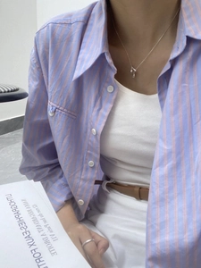 Close-up of S925 silver blue teardrop pendant necklace with striped shirt and white vest