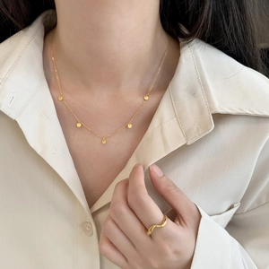 Close-up of minimalist gold 925 sterling silver mini round necklace and wave shaped ring
