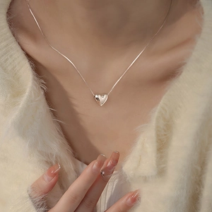 Close-up of minimalist S925 silver heart pendant necklace on a female collarbone