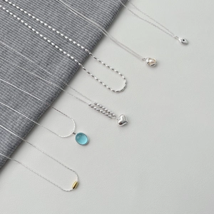 Detailed flat lay of S925 sterling silver necklaces featuring pearls and heart pendants