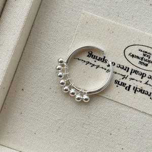 Macro detail of S925 sterling silver ball cluster ring on elegant fabric background