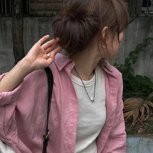 Détail du mannequin portant des créoles minimalistes en argent et une chemise en lin rose