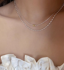 Dettaglio di una collana a doppio strato in argento S925 con grani d'oliva e ciondolo oro