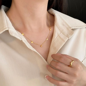 Detail of 925 sterling silver gold minimalist disc necklace and wavy ring on a model