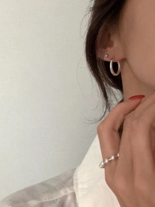 Gros plan de créoles minimalistes en argent 925 et d'une bague à perles sur un mannequin
