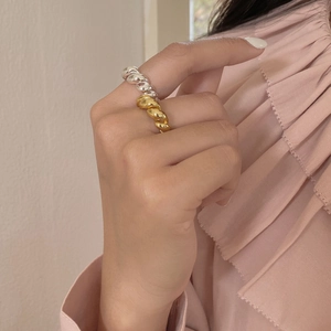 Detailansicht verschlungener gedrehter Seilringe in Gold und Silber auf dem Finger
