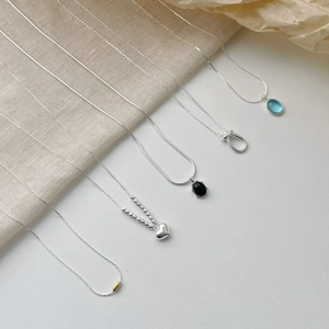 Elegant S925 sterling silver necklaces featuring heart and black agate pendants on linen