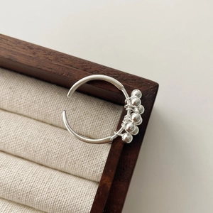 Detail of S925 sterling silver open ring with five polished beads on a jewelry box