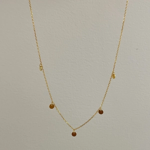 Close-up of minimalist 925 silver golden necklace featuring five small round disc pendants
