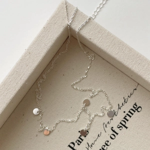Detailed view of minimalist S925 sterling silver necklace with five round disk pendants