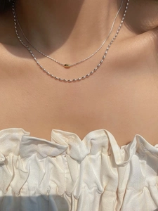 Dettaglio di collana S925 in argento a strati con perla dorata indossata dal modello